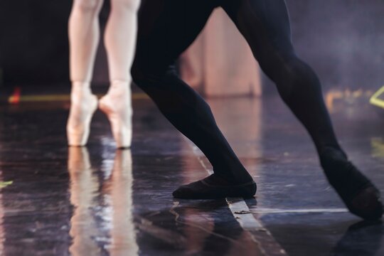 Ballet dancers couple during performance repetition, classic ballet rehearsal practicing in ballroom, view of legs in pointe shoes, ballerina and ballet dancer on a concert hall theatre stage floor