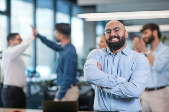 A man in a blue shirt is posing for a picture with his arms crossed