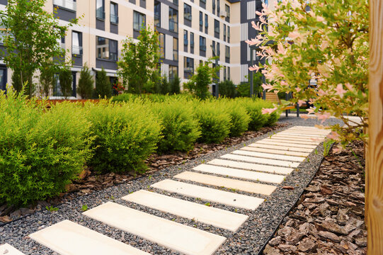 Modern courtyard with walkway and greenery. Landscaping in a residential complex. Urban outdoor space.