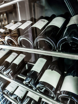 Rows of wine bottles stored horizontally in a modern climate-controlled cellar refrigerator.