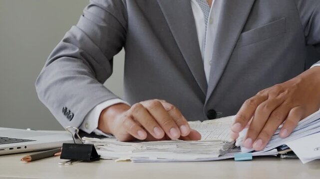 Business professional sorting a large stack of office paperwork, symbolizing heavy workload, deadline stress, file organization, report review, daily administration, and corporate processing.