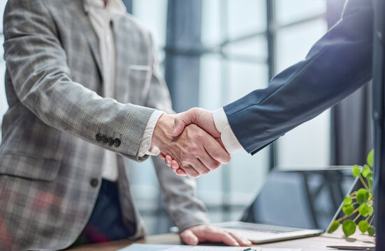 Two professionals shake hands in a modern office