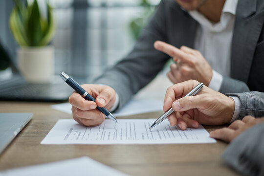 Two professionals review documents at a wooden desk