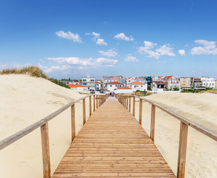 A wooden boardwalk path leading through sand dunes towards the Atlantic coast
