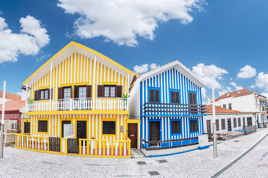 Iconic wooden houses with colorful vertical stripes under a clear blue sky in Costa Nova, Portugal.