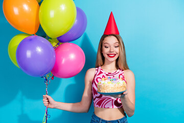 Obraz premium Joyful young woman celebrating with balloons and cake against a vibrant background