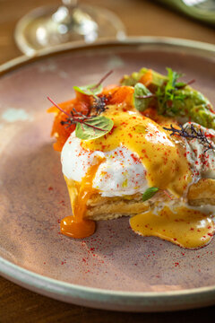 Elegant brunch dish with poached eggs hollandaise sauce and fresh vegetables served on ceramic plate