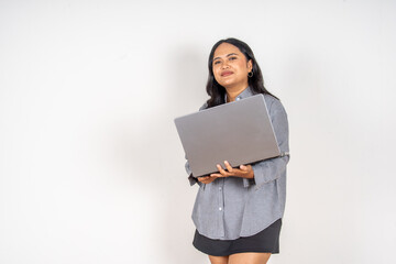 Obraz premium Young woman holds laptop with a joyful expression. She wears a casual striped shirt and dark skirt. Her gaze upward suggests excitement or inspiration. Simple white background highlights her