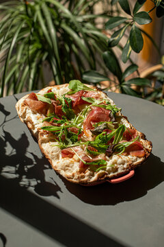Crispy roman style pizza topped with prosciutto arugula cheese and fresh greens