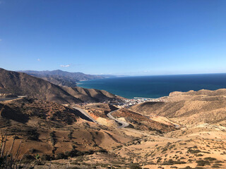 Obraz premium Winding road descending arid mountains to coastal town