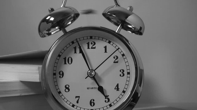 Black and white style of an alarm clock set for 5 am	
