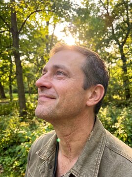Proud male cancer survivor looking up at the sky with hope in nature park