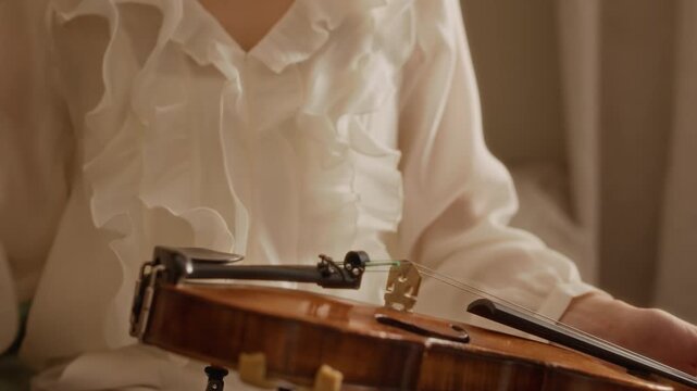 Cropped shot of woman attaching shoulder rest to violin and preparing bow for music lesson. Clip is ideal for music school promos and private tutoring advertisements