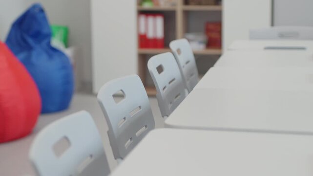 Empty study tables stand neatly arranged for upcoming lesson in clean academic facility. Neutral tones offer elegant structured feel