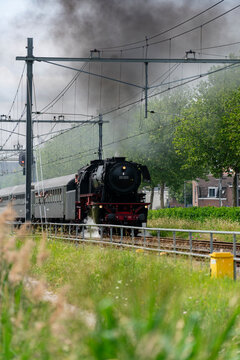 Vintage steam locomotive pulls historic passenger carriages through Dordrecht during Dordt in Stoom 2026. Ideal for transport, heritage and railway event concept.