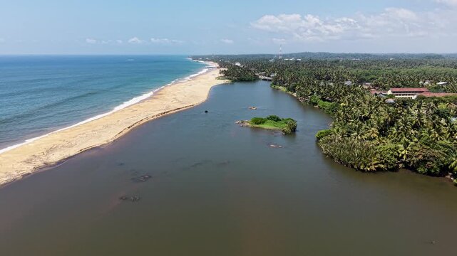 Aerial view of Mahamodara Lake separated from the ocean by a sandy beach with lush palm trees and buildings Galle, Southern Province, Sri Lanka.