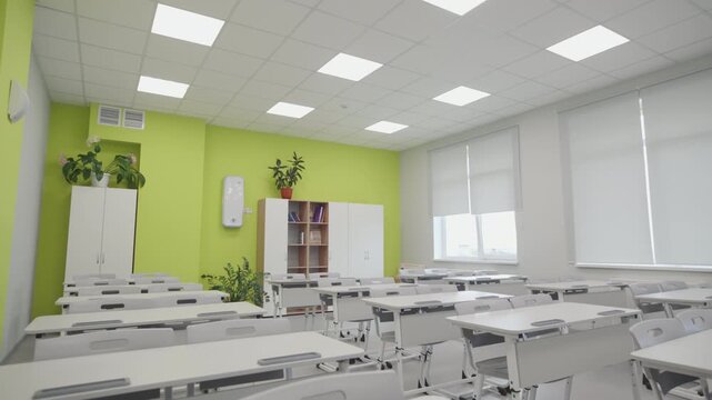Grid ceiling with square LED panels fills empty room with crisp illumination. Large windows with blinds provide additional soft daylight