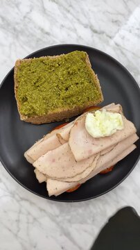 A delicious and aromatic Italian-inspired sandwich featuring basil pesto, whole wheat  bread, and fresh ingredients like mozzarella, tomatoes, and Turkey ham.