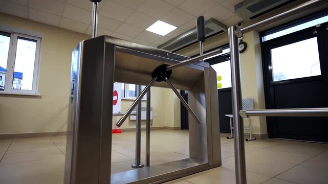 Tripod turnstile gate made of brushed stainless steel controls entry access. Checkpoint equipped with automated glass door exit system