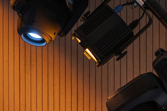 Two professional stage spotlights cast warm and cool beams across vertical wood panels, emphasizing lighting equipment, texture and mood for theater, studio or event production