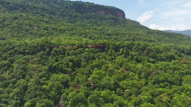 Aerial drone footage of the dramatic flat-top mesa and agricultural valley near Khamtay Cave viewpoint, Attapeu Province, southern Laos. The drone reveals the sweeping landscape of patchwork rice padd