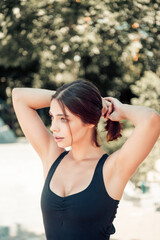Young woman tying her hair before an outdoor workout — fitness portrait of a healthy, active...