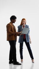 Fototapeta premium Business colleagues reviewing laptop together in white studio. Concept of digital collaboration, startup planning, corporate strategy, office technology, and teamwork culture.