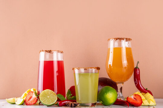 Fricy flavours bar drinks concept with three various sweet and spicy cocktails with chili peppers, strawberry, lime, spices, mango, peach, fruit juices, viral summer refreshing beverages ideas