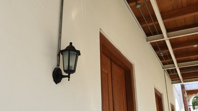 An iron decorative lamp is mounted on the wall of an old house.