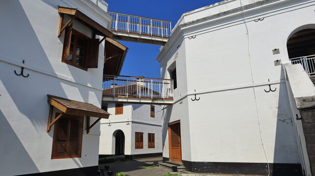 Two white iron bridges connect the two buildings at the second-floor level and at the roof.