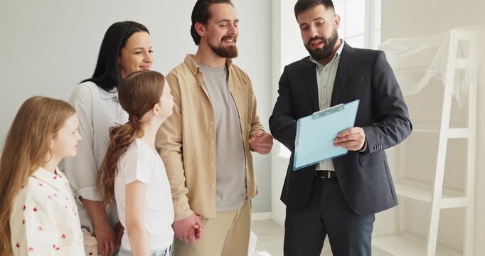 Family parents mother father daughters with agent moving. Smiling children and a trusted realtor review forms in a bright home, planning relocation and ownership. Concept moving to new home