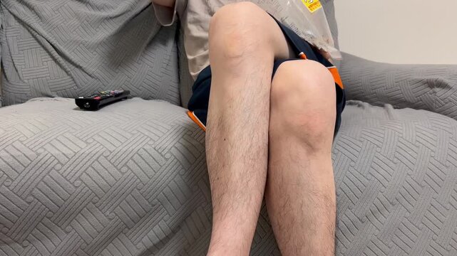 ソファーでくつろぎながらお菓子を食べる男性