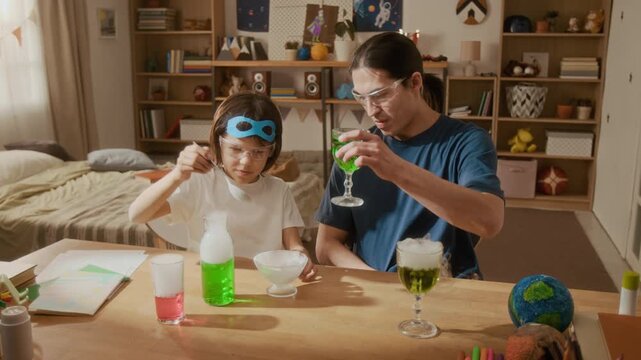 Man and child wearing safety goggles conducting science experiment with dry ice at home. Clip perfect for STEM education campaigns, parenting blogs, and e-learning advertisements