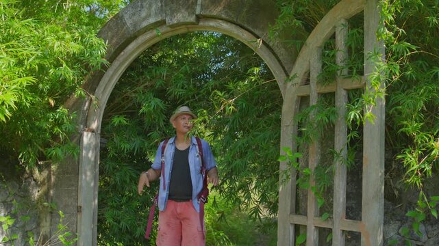 Adventurer Entering an Abandoned Building Through an Old Gate Overtaken by Dense Bamboo Vegetation, Capturing Wilderness Discovery. 
