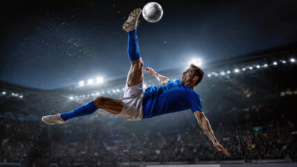 Cinematic action shot of a professional soccer player in blue jersey performing a bicycle kick in a crowded stadium at night, athlete making an overhead goal under bright floodlights.