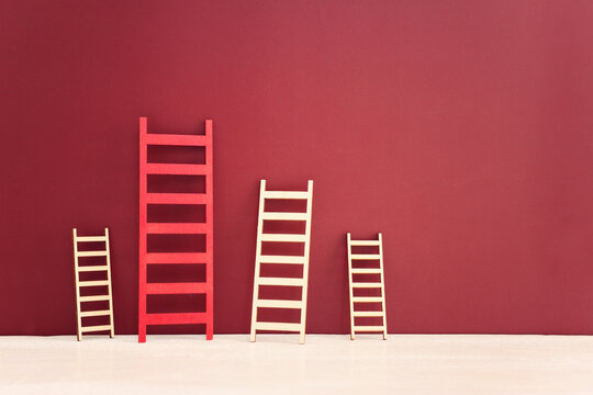 Red ladder among group of smaller ones. Concept of aiming high and achieving success