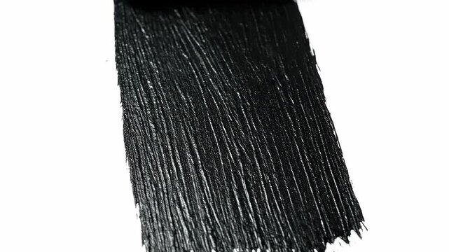 Close-up of a paint roller applying a thick layer of black paint to a white surface in a vertical motion, showing texture and contrast. Concept of renovation and minimalism.