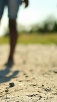 Vertical video: Tracking camera capturing two adults walking sandy path, light shorts, copy space