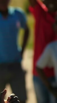 Vertical video: Soccer ball entering left urging teens in tees reaching, catching in sand for play