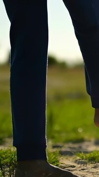 Vertical video: Rolling soccer ball right, kid's feet trapping it on sand, navy sweats to control
