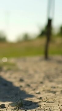 Vertical video: Shifting teen in cuffed pants trapping soccer ball on sand to play, copy space