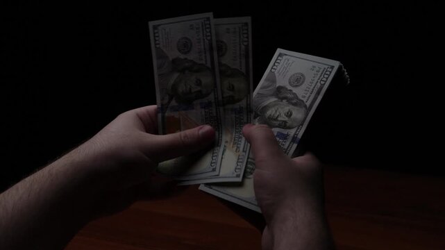 A man counts money. A stack of dollar bills in his hands