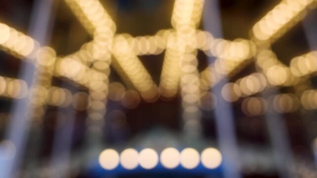 Abstract bokeh of spinning vintage carousel lights in dark amusement park