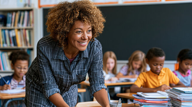 A smiling teacher helps young students focused on their schoolwork in a classroom setting filled with books and a chalkboard.