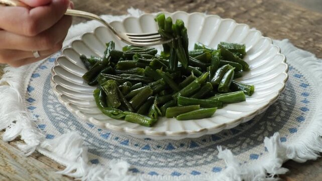 Person eating cooked green beans. Healthy vegan plant based meal for breakfast or dinner