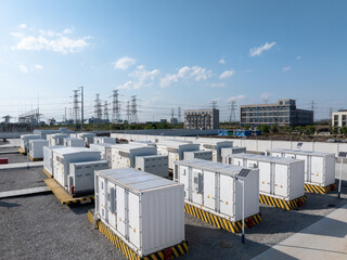 Fototapeta premium Outdoor energy storage container array at substation with power lines and buildings