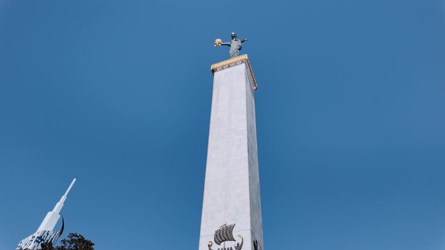 Beautiful view of the monument of medea with the golden fleece in europe square, batumi, georgia, framed by lush green palm trees against a clear blue sky on a sunny summer day
