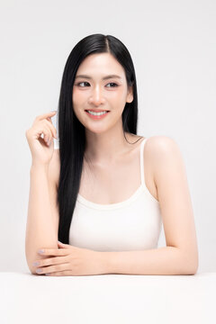 Portrait of beautiful Asian young woman with clean fresh glowing skin and long straight black hair, smiling, beauty and skincare concept, isolated on white background.