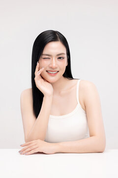 Portrait of beautiful Asian young woman with clean fresh glowing skin and long straight black hair, smiling, beauty and skincare concept, isolated on white background.