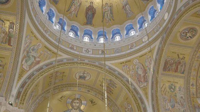 Breathtaking golden mosaics inside the Church of Saint Sava in Belgrade. Majestic view of Jesus Christ Pantocrator on the cathedral dome ceiling and chandelier chains. Belgrade, Serbia 22.05.2026